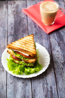 Ahşap bir arka plan üzerinde peynir, domates, salatalık, sosis ve marul ile Sandviç. Dikey yönlendirme