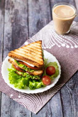 Ahşap bir arka plan üzerinde peynir, domates, salatalık, sosis ve marul ile Sandviç. Dikey yönlendirme