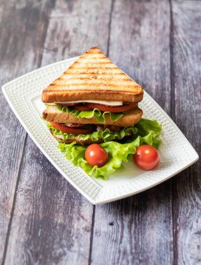 Ahşap bir arka plan üzerinde peynir, domates, salatalık, sosis ve marul ile Sandviç. Dikey yönlendirme