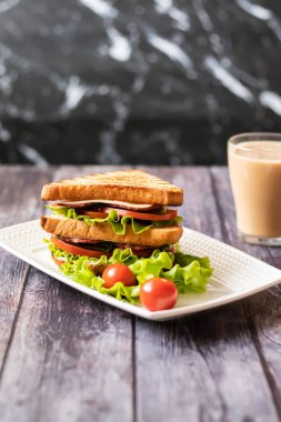 Ahşap arka plan üzerinde peynir, domates, salatalık, sosis ve salata ile Sandviç. Sütlü kahve. Dikey yönlendirme
