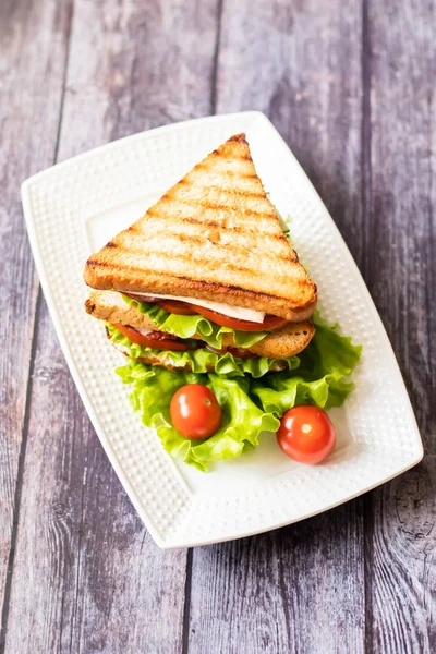 Sandwich with cheese, tomato, cucumber, sausage and lettuce on a wooden background. Vertical orientation — Stock Photo, Image