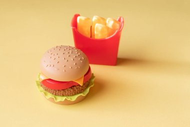 Plastik burger, salata, domates, sarı bir arka plan üzerinde patates kızartma. Yatay yönlendirme. Çocuk oyuncakları. Zararlı yapay gıda kavramı. Plastik organik değil. Sağlıklı değil.