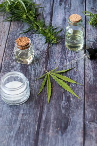 Cannabis hemp creams with marijuana leaf on wooden background - topical cannabis oil concept