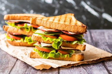 Ahşap arka plan üzerinde peynir, domates, salatalık, sosis ve salata ile Sandviç. Yatay yönlendirme