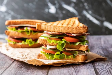 Ahşap arka plan üzerinde peynir, domates, salatalık, sosis ve salata ile Sandviç. Yatay yönlendirme