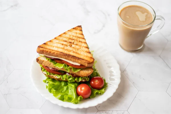 Sandwich with cheese, tomato, cucumber, sausage and salad on a light background. Coffee with milk. — Stock Photo, Image