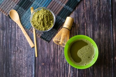 ahşap bir yüzey üzerinde bir kase yeşil çay matcha. Üst görünüm, antioksidanlar, detoks içerir. Yatay yönlendirme