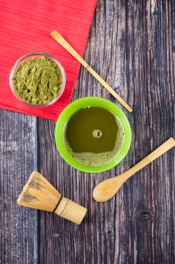 Kırmızı bir peçete ile ahşap bir yüzey üzerinde bir kase içinde maç yeşil çay. Üst görünüm, antioksidanlar, detoks içerir. Dikey yönlendirme