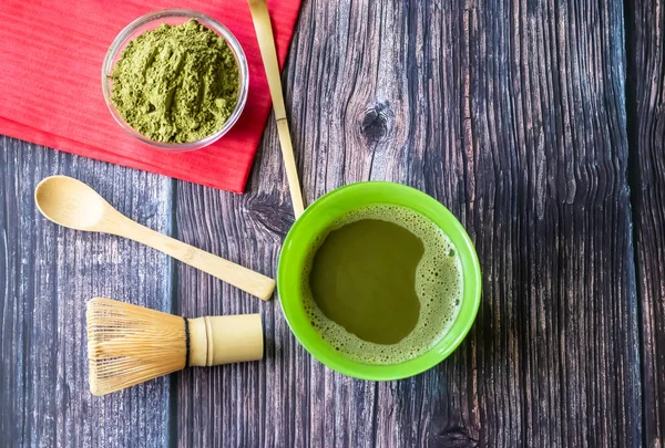 Abbina il tè verde in una ciotola su una superficie di legno con un tovagliolo rosso. Vista dall'alto, contiene antiossidanti, disintossicazione. Orientamento orizzontale — Foto Stock