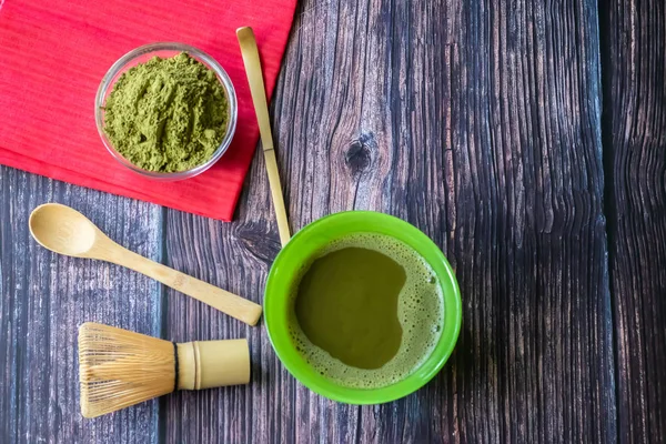 Kırmızı bir peçete ile ahşap bir yüzey üzerinde bir kase içinde maç yeşil çay. Üst görünüm, antioksidanlar, detoks içerir. Yatay yönlendirme