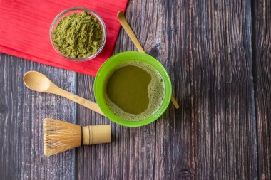 Kırmızı bir peçete ile ahşap bir yüzey üzerinde bir kase içinde maç yeşil çay. Üst görünüm, antioksidanlar, detoks içerir. Yatay yönlendirme