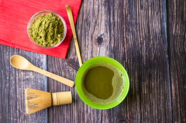 Kırmızı bir peçete ile ahşap bir yüzey üzerinde bir kase içinde maç yeşil çay. Üst görünüm, antioksidanlar, detoks içerir. Yatay yönlendirme