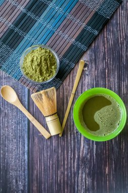 ahşap bir yüzey üzerinde bir kase yeşil çay matcha. Üst görünüm, antioksidanlar, detoks içerir. Dikey yönlendirme