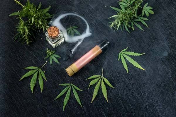 Líquido de cannabis. Vape CBD o THC, Vaping Marijuana Leaves and Hemp. Sobre un fondo oscuro. Puffs de humo . —  Fotos de Stock