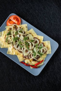 Besthe mak ulusal bir Kazak yemeğidir. Haşlanmış et ve soğanlı kare makarna. Siyah bir arkaplanda