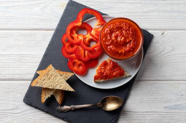 Ajvar veya pindjur kırmızı sebze sosu, kara tahtada kırmızı biber ve ahşap masa. Sırp geleneksel yemekleri.