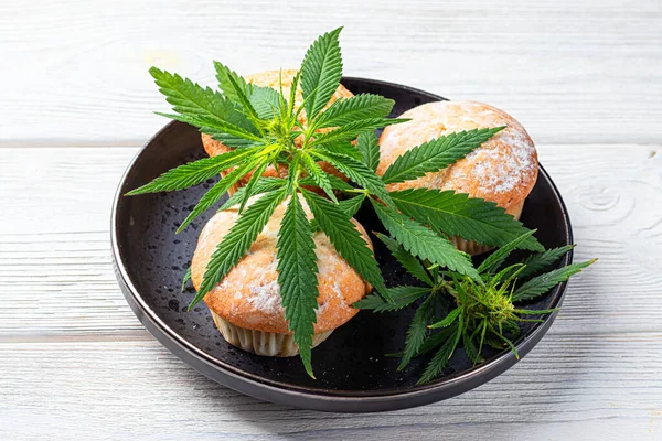 Cannabis och muffins med marijuana på svart tallrik, konceptet medicinsk marijuana, hemlagad mat. Utsikt ovanifrån Stockbild