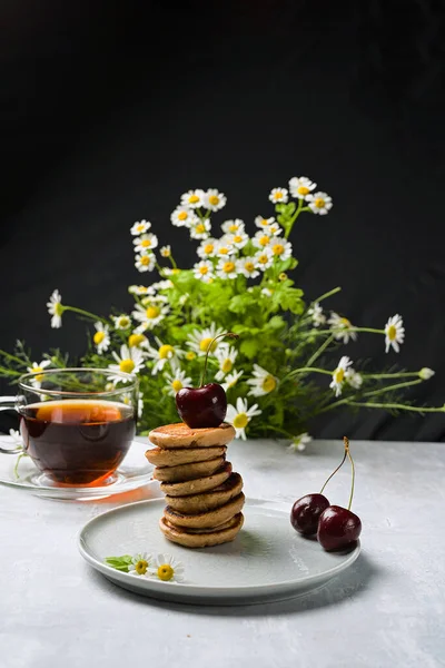 Mini crêpes aux fruits et varenie sur une assiette aux cerises et camomilles en arrière-plan. Orientation verticale — Photo