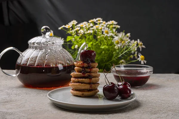 Un petit déjeuner maison branché avec mini crêpes et cerises sur la table. — Photo