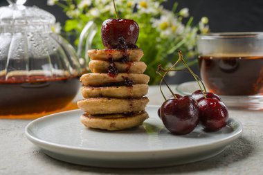 Modaya uygun ev yapımı, küçük krepli bir kahvaltı. Mini krep, kiraz, masada çay..