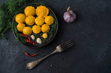 Biber, sarımsak ve dereotla marine edilmiş küçük kabak, ev yapımı. Siyah taş bir masanın üzerinde. Yukarıdan bak. Uzayı kopyala Yatay yönelim