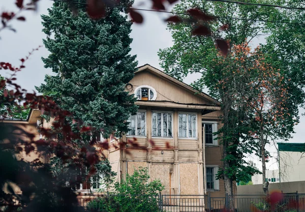 Eski ahşap, iki katlı apartman dairesi sonbahar ağaçları arasında ışık saçar.