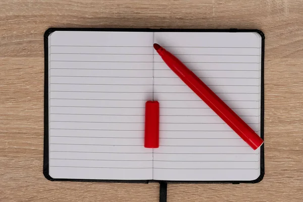 Red pen on open notepad on wooden desk