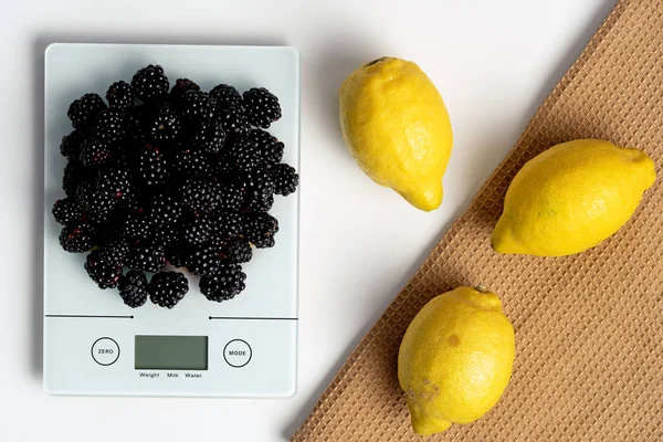 Lemons on brown towel and scale with blackberries
