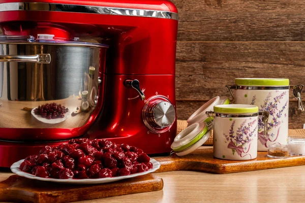 Red stand mixer, sour cherries and container jars for flour and sugar with a brown cloth