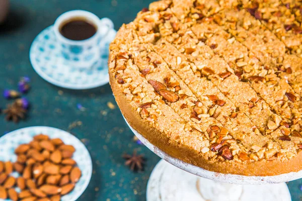 Couper le gâteau sur la table avec des amandes et une tasse de café — Photo