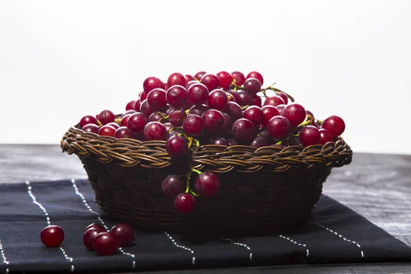 Wicker basket with grapes on table runner with white background