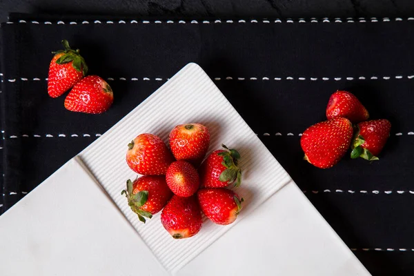 Arranged strawberries in plate on table with scattered berries — Stock Photo, Image