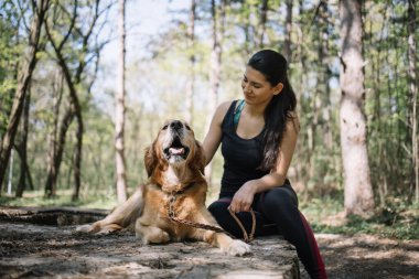 Doğada köpeğinin yanında oturan mutlu kız.
