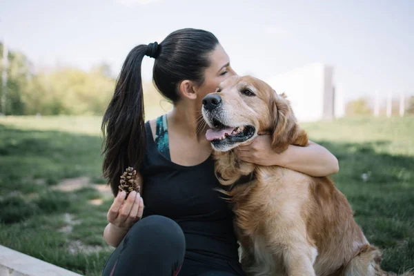 Şehir parkında köpeğine sarılan bir kadın.