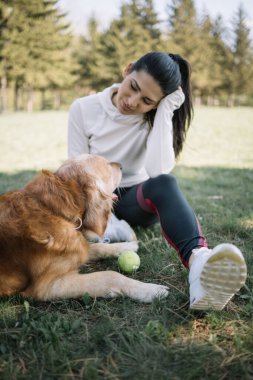 Kız ve köpek ormanda çayırda dinleniyor.