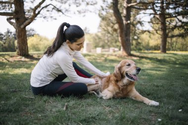 Kız ve köpek parkta yerde yatıyor.