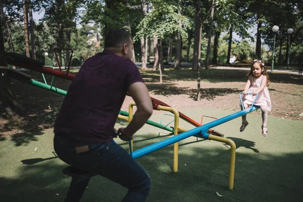 Hombre y chica jugando en el balancín al aire libre —  Fotos de Stock
