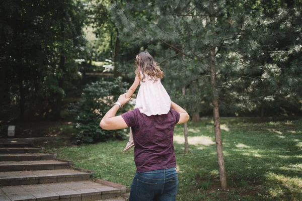 Widok z tyłu ojca z córką na ramionach — Zdjęcie stockowe