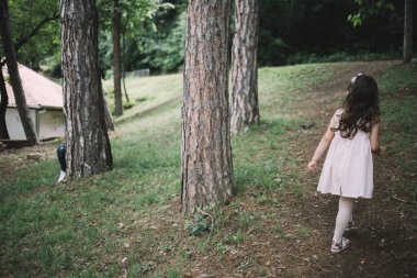 Baba ve çocuk parkta saklambaç oynuyorlar.