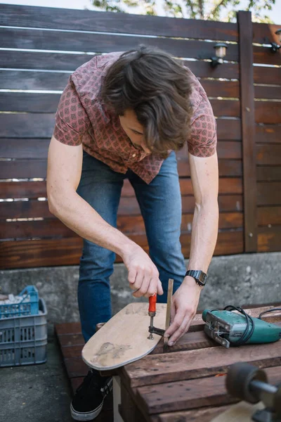 Man with screwdriver fitting up skateboard with tires