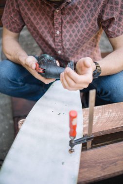 Erkek ellerinin zımpara makinesi ve zımpara kağıdı tutarken yakın plan görüntüsü