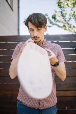 Odaklanmış adam cilalanmamış yerler için parlayan tahtayı kontrol ediyor