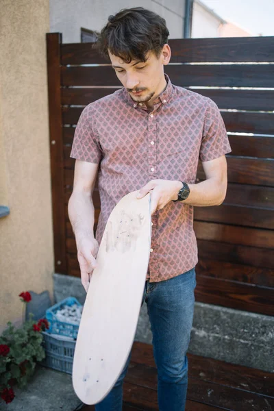 Vážný muž drží dřevěnou desku a hledá vady — Stock fotografie