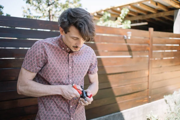 Mladý muž drží nástroje při stání venku — Stock fotografie