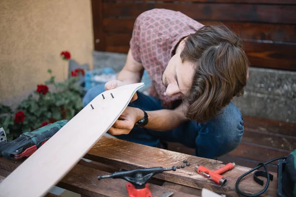 뒷마당에 스케이트보드 부품을 조립하는 사람에게 초점을 맞춘 사람 — 스톡 사진