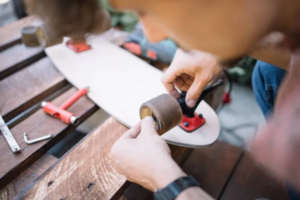 Close-up view of male hands fitting wheel to skateboard — Stock Photo, Image