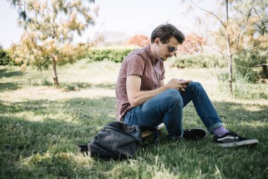 Yerde otururken akıllı telefon kullanan bir adamın portresi