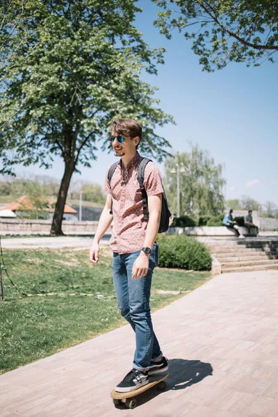 Schöner Kerl bewegt sich mit Skateboard im Park — Stockfoto