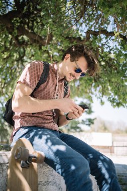 Ağacın altında telefon kullanan gülümseyen adamın portresi