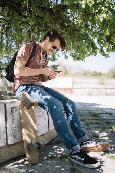 Mann mit Handy ruht sich an sonnigem Tag im Freien aus — Stockfoto